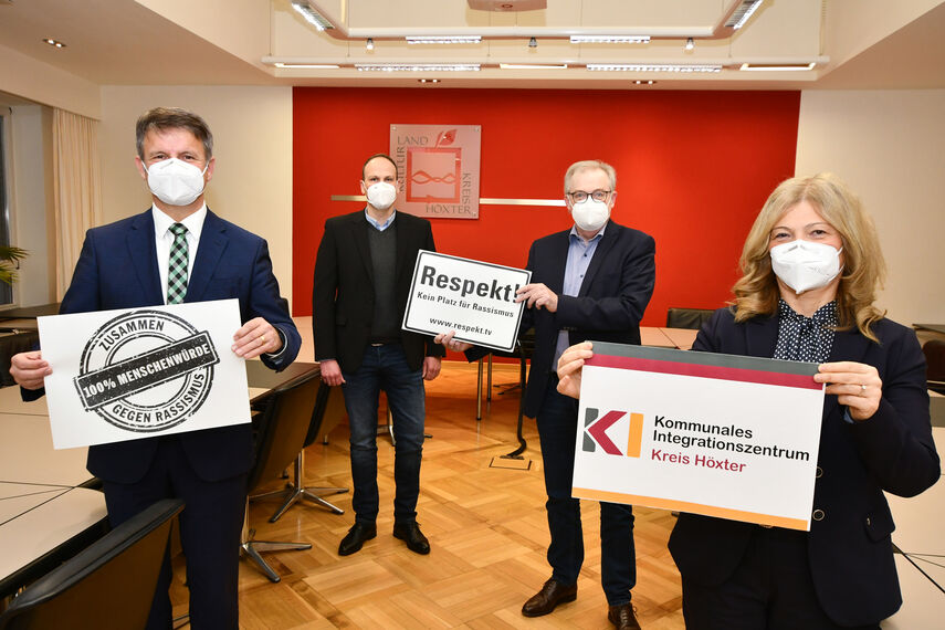 Landrat Michel Stickeln, Domenic Gehle, Klaus Schumacher und Filiz Elüstü halten im Sitzungsraum in der Kreisverwaltung Schilder in der Hand, die auf die Woche gegen Rassismus hinweisen.