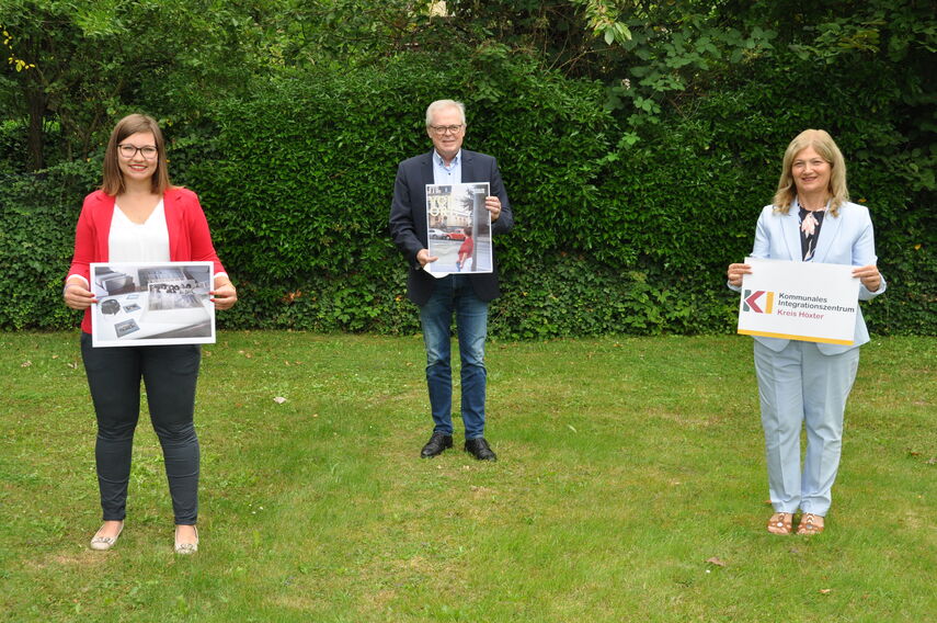 Alexandra Schodrowski, Klaus Schumacher und Filiz Elüstü stehen auf einer Wiese und halten Plakate in den Händen.