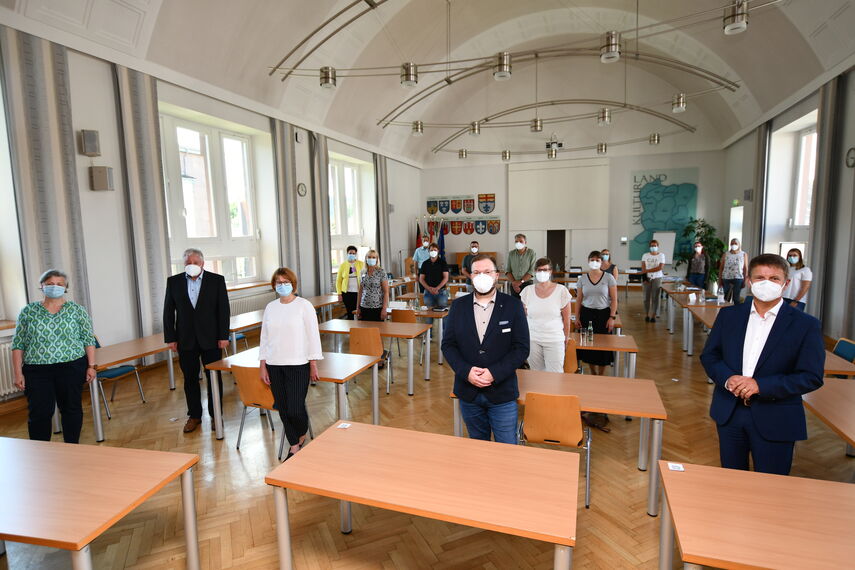 18 Mitglieder des Netzwerks Pflege stehen Coronabedingt mit Maske in der Aula des Kreishauses in Höxter.