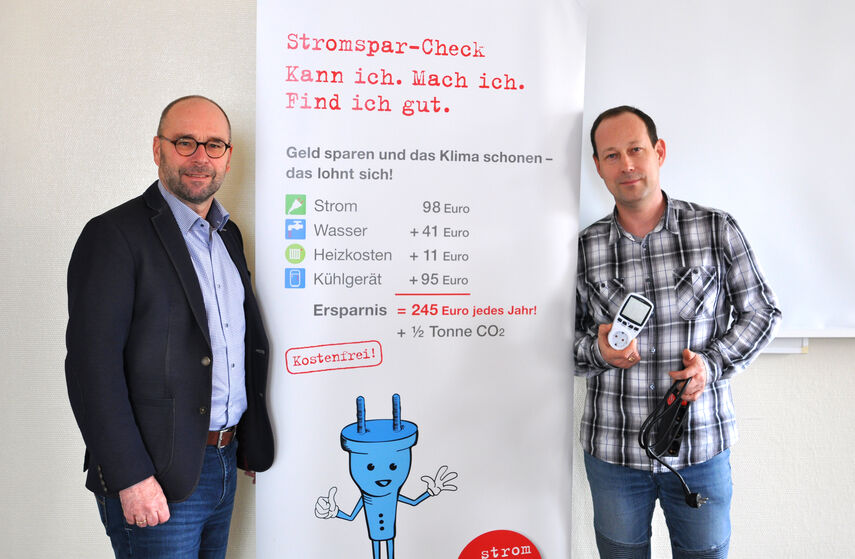 Fachbereichsleiter Michael Werner und Projektleiter Maksim Boschmann vor einem Rollbanner zum Thema Stromspar-Check.