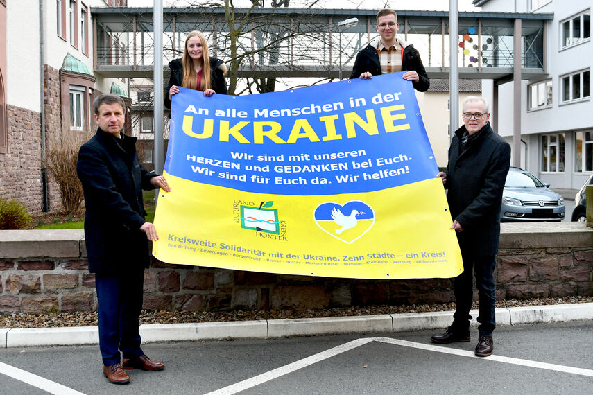 4 Personen stehen vor dem Kreisgebäude in Höxter und halten einen großen Banner mit einer Botschaft für die Ukraine in den Händen.