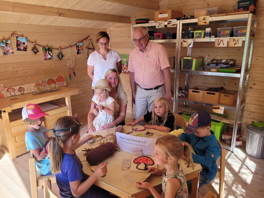 6 Kindergarten-Kinder basteln in der Holzwerkstatt und 3 Erwachsende schauen ihnen zu.