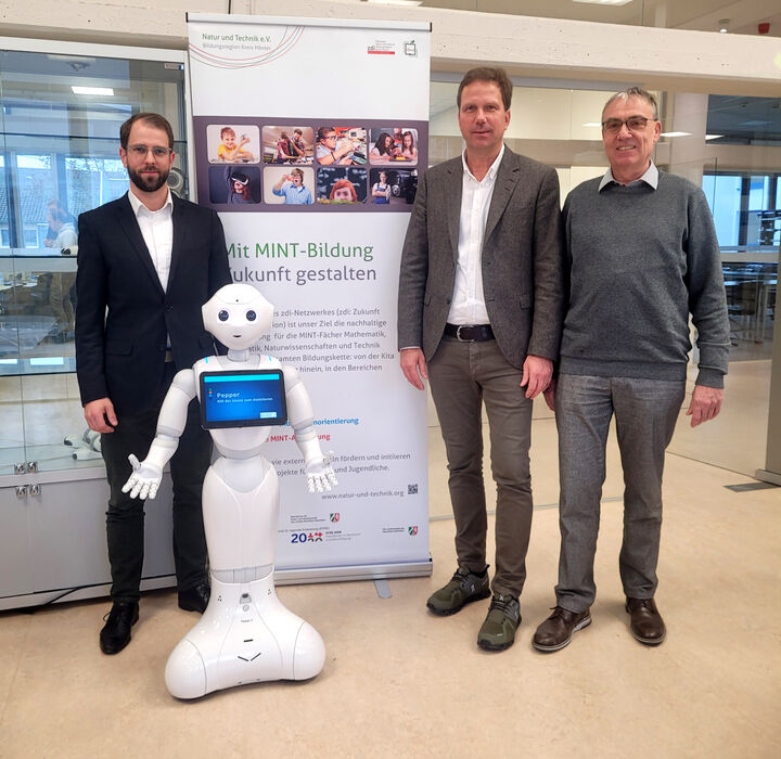 Nils Dorn, Michael Urhahne und Peter Gronemeyer stehen vor einem Roboter.